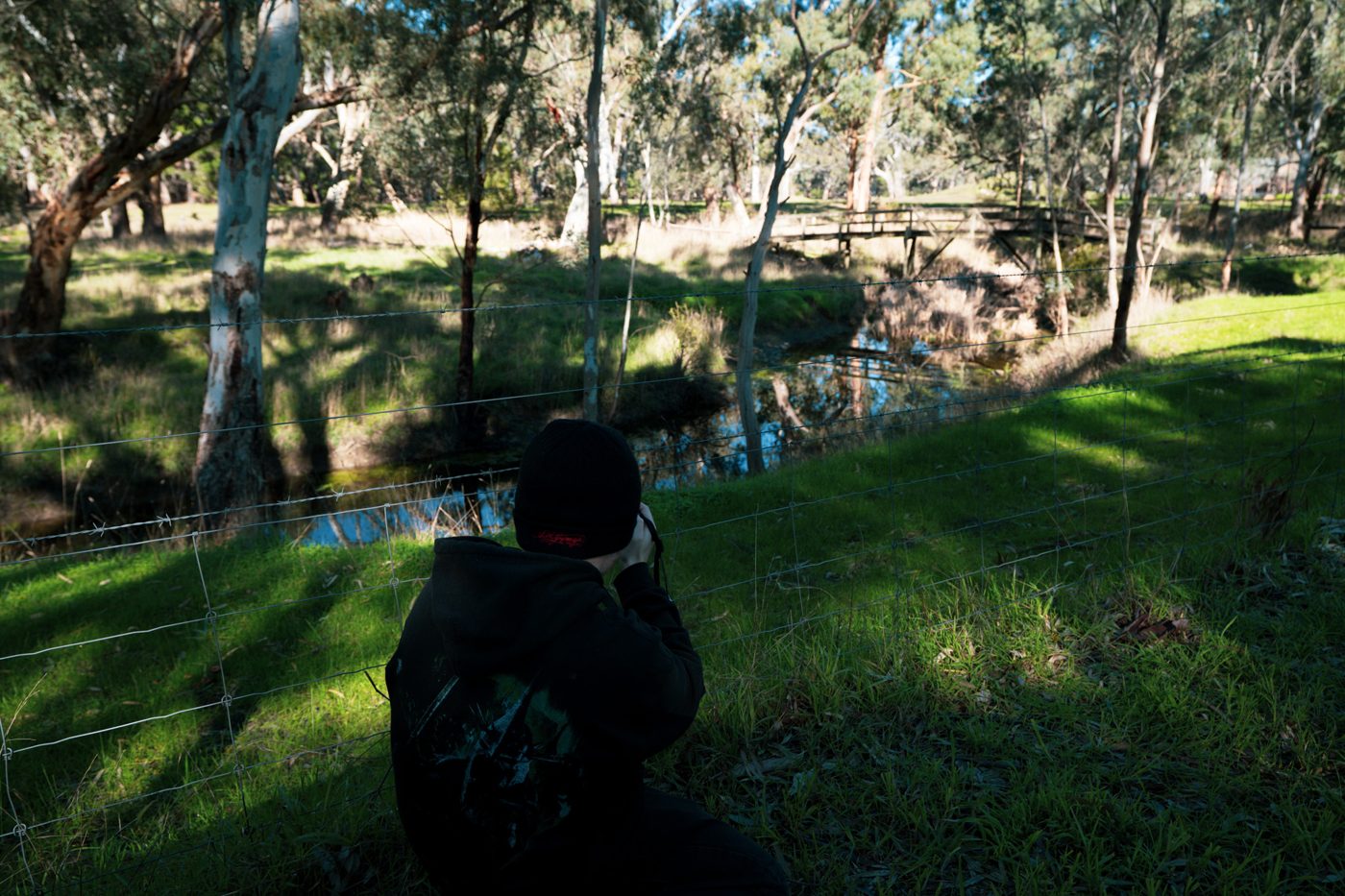 Shane Leigh photographing beside a creek in the countryside